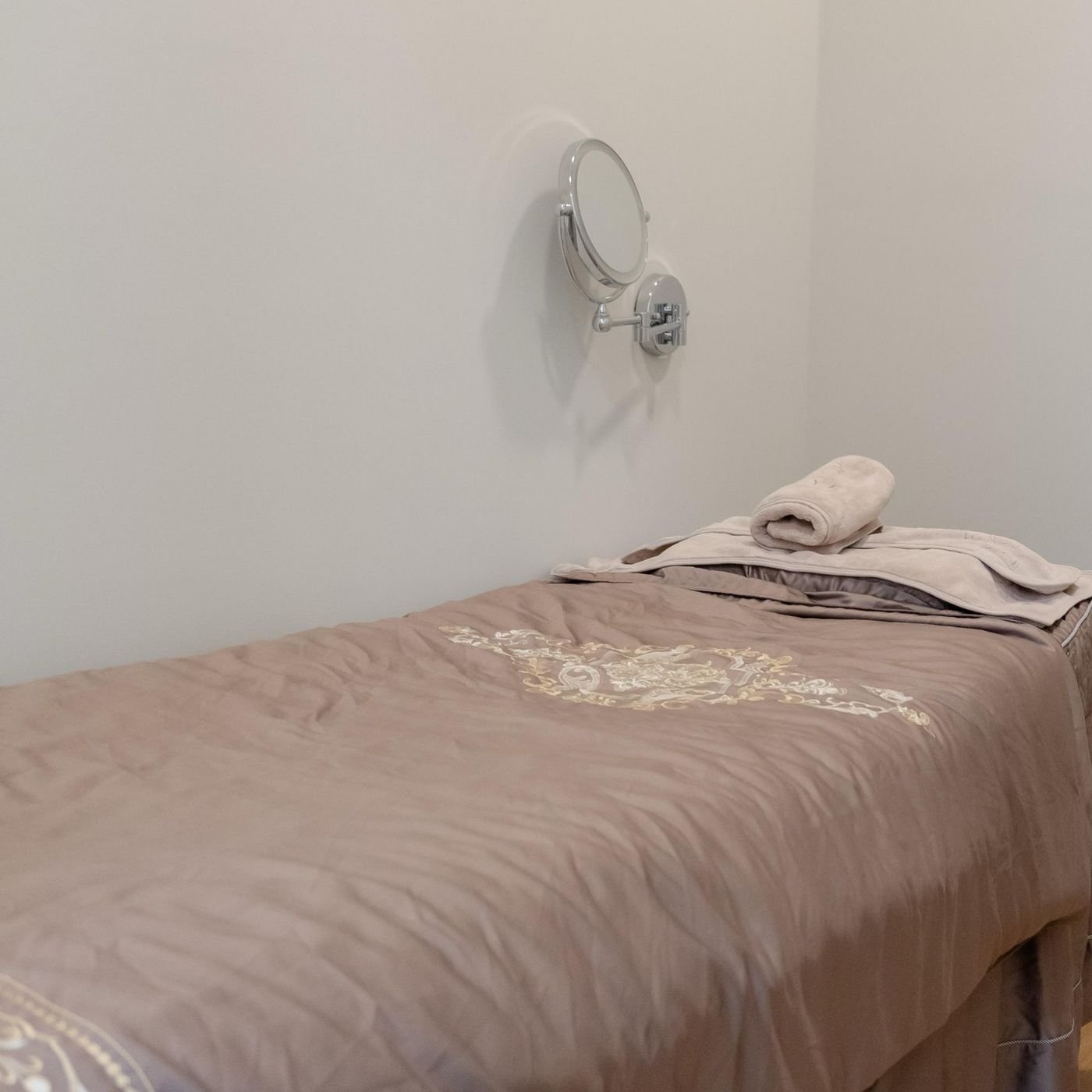 Facial treatment bed dressed in soft mauve linen