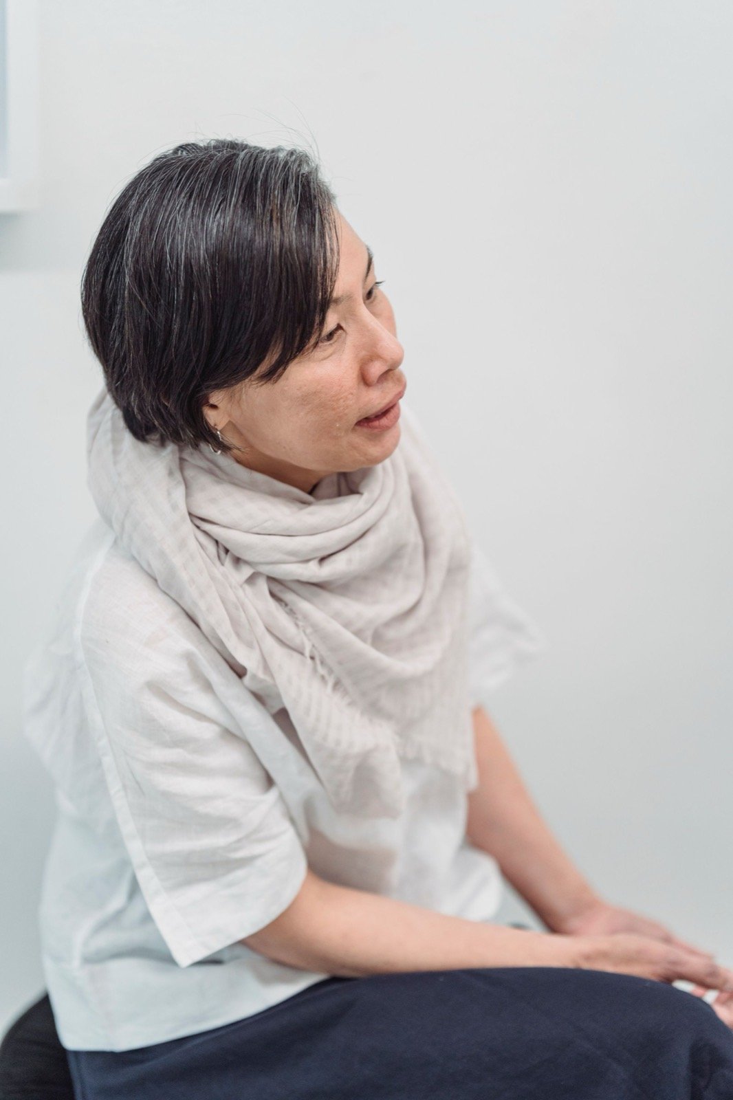 Mature woman in a soft scarf sitting calmly by a window